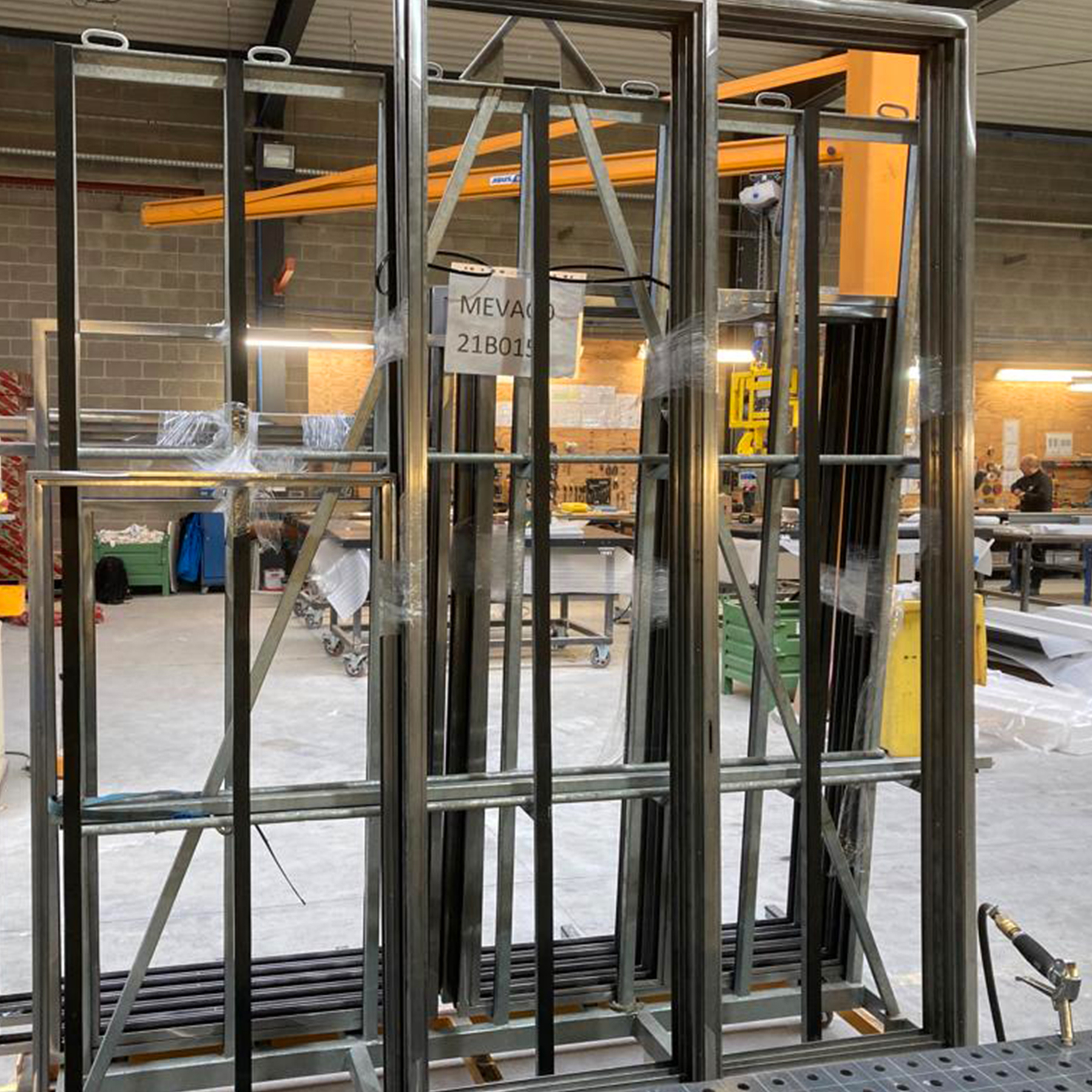 De metalen raamgehelen staan klaar op bokken voor de volgende stap in het productieproces.